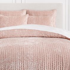 a bed with pink bedspread and white pillows