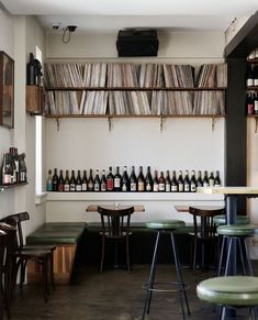 there are many bottles of wine on the shelves in this room, along with several stools