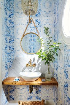 a white sink sitting under a mirror next to a wooden shelf with a potted plant on it