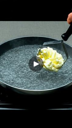 a person is using a knife to cut up some food in a pan on the stove