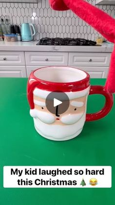 a red and white mug with a face on it sitting on top of a counter