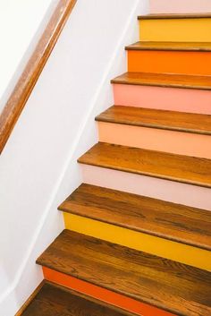 an orange and yellow stair case next to a wooden hand rail