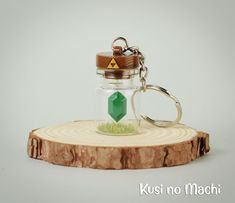 a glass keychain with a green diamond in it sitting on a piece of wood