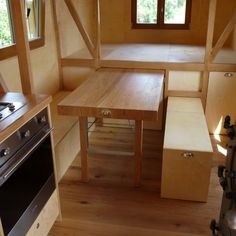 a kitchen area with wooden cabinets and counter tops in a tiny home on wheels that is built into the side of a trailer