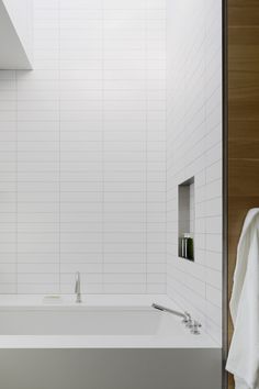 an empty bathroom with white tile on the walls and floor, along with a bathtub