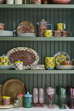 the shelves are filled with colorful dishes and cups