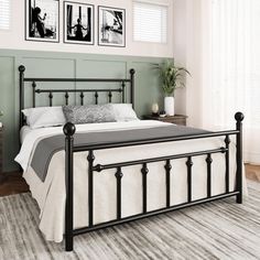 a black metal bed frame in a bedroom with two pictures on the wall above it