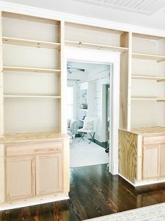 an empty living room with white walls and wooden shelves on the wall, along with hardwood flooring