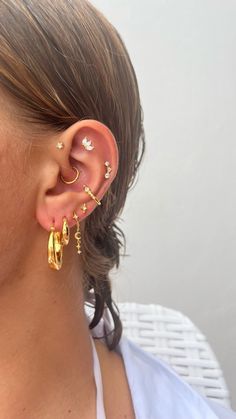 a close up of a person wearing ear piercings with gold colored beads and leaves on them