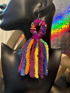 a pair of multicolored tasselled earrings on a mannequin head