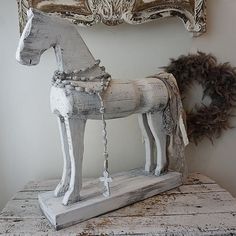 a white horse statue sitting on top of a wooden table next to a framed mirror