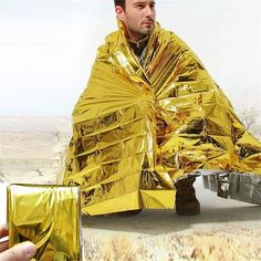 a man is sitting on the ground with an umbrella wrapped around his body and holding a gold wallet