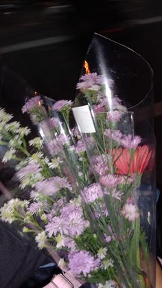 a vase filled with lots of flowers on top of a table next to a person