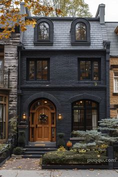 a black brick house with two story windows and an entryway leading to the front door