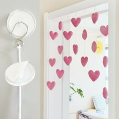 pink hearts are hanging from the wall next to a white door with a mirror on it