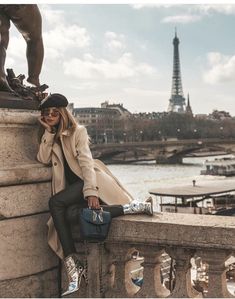 a woman leaning against a wall next to a statue