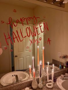 a bathroom sink with candles on it and the words happy halloween spelled in red ink