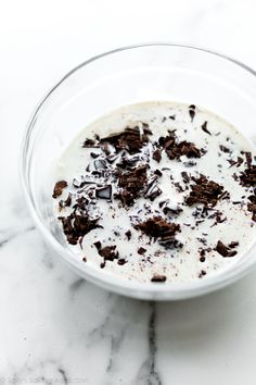 a bowl filled with milk and chocolate chips on top of a marble countertop next to a white wall