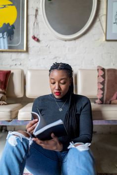 a woman sitting on a couch reading a book