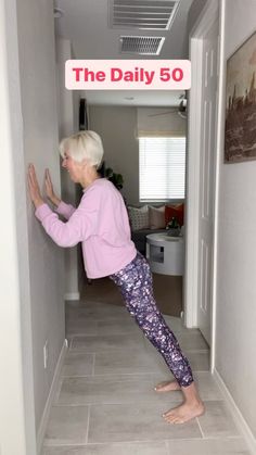 an older woman is doing yoga in the hallway