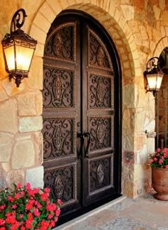 an entrance to a home with two large doors and flowers in the planters outside