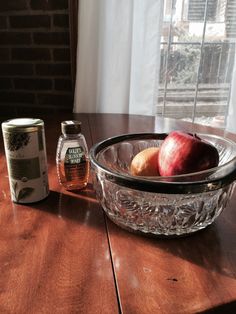 apples and honey sit on a table in front of a glass bowl with an apple