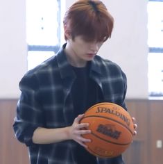 a young man holding a basketball in his hands