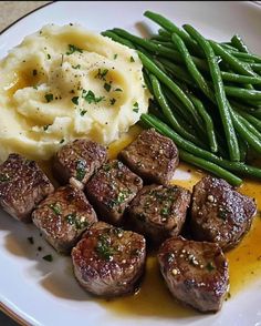 a white plate topped with meat, mashed potatoes and green beans