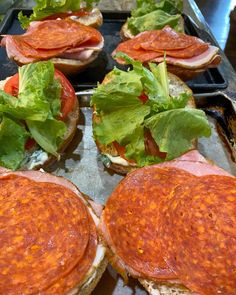 several sandwiches with lettuce and tomato on them are ready to be cooked in the oven