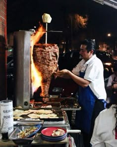 a man cooking food on top of a grill with flames coming out of the back