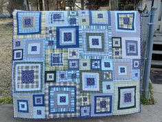 a blue and green patchwork quilt hanging on a fence