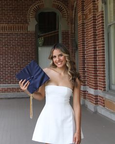 a woman in a white dress holding a blue graduation cap