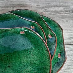 three green plates sitting on top of a wooden table