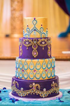 a three tiered cake with blue and yellow frosting on the top, sitting on a table