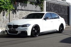 a white car parked in front of a building on the side of the road with black rims