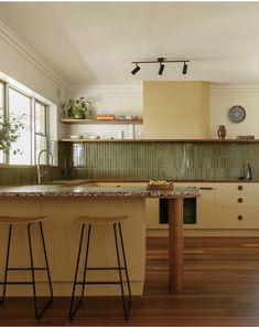 a kitchen with two bar stools in front of the counter and an island next to it