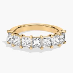 a yellow gold ring with princess cut diamonds on the sides and four stones in the middle