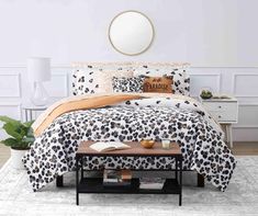 a bed with black and white animal print comforter on top of it next to a coffee table