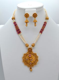 This beautiful antique gold pendant features Kemp stones and American diamonds, paired with a Pearl Mala Necklace and earrings set. This exquisite necklace enhances your style for any occasion, adding sparkle whether you wear it with a dress or a stunning saree. Necklace Length: 11.5" and can be adjusted with a chain. Earring length: 1.5" with push-back closure Antique gold Polish and High-quality brass as the base metal Availability: In-Stock. *Color may vary slightly due to light condition & p Elegant Dual-tone Temple Necklace For Puja, Elegant Dual-tone Necklace For Puja, Gold Cutdana Necklaces For Anniversary, Bollywood Style Gold Necklace With Matching Earrings, Gold Cutdana Necklace For Anniversary, Gold Necklace With Cutdana For Anniversary, Traditional Pendant Jewelry Sets For Anniversary, Festive Temple Jewelry Sets For Anniversary, Traditional Bridal Necklace With Matching Earrings For Anniversary