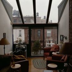 a living room filled with lots of furniture next to a tall brick building on top of a roof