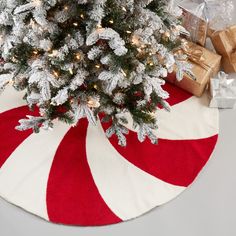 a christmas tree with presents under it on a red and white striped round area rug