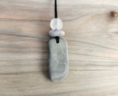 Handmade, one of a kind, beach stone necklace inspired by the beauty of nature. It's a little piece of the beach for you to hold onto and wear all year round. It will also make a lovely gift for anyone who loves being reminded of the peaceful feeling that comes from a walk along the beach or through the woods. All stones are "perfectly imperfect", just as you would find them in nature and are not treated or polished. Materials for this item: natural beach stones, recycled glass bead, waxed cotton cord (black).  Necklace cords are made from waxed cotton and measure approximately 34"-36" long. Cord is very strong and has a simple tie knot that you can shorten easily. All pieces are handmade in my home shop in Massachusetts and shipped in a lovely little gift bag. I recycle and reuse packagin Long Beach Necklace With Natural Stones, Nature-inspired Beach Jewelry With Natural Stones, Simple Tie Knot, Nature-inspired Natural Stones Necklace For Beach, Beach Rock Necklace, Beach Multi-strand Natural Stone Jewelry, Beach Stones Jewelry, Natural Stone Necklace, Recycled Glass Bead