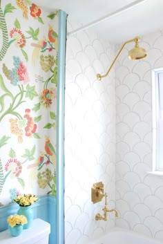 a white toilet sitting next to a bath tub in a bathroom under a wall paper