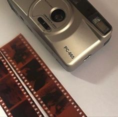 a silver camera sitting on top of a table next to a roll of film and a pair of scissors