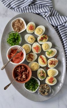 an assortment of deviled eggs on a platter with dipping sauces and seasonings