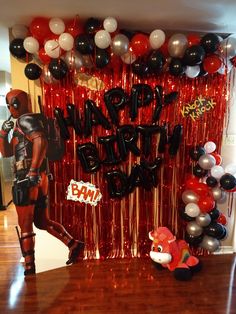 a birthday party with balloons and decorations on the wall, including an image of deadpool