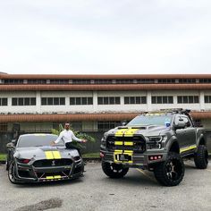 two trucks parked in front of a building with a man standing next to one car