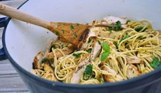 a pan filled with pasta and chicken next to a wooden spoon