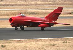 a small red plane is on the runway