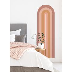 a bed in a bedroom with a pink and orange striped wall decal next to it